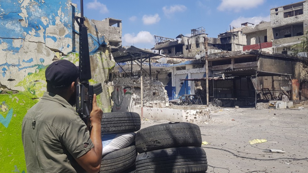 En Fatah-soldat står vakt intill förstörda byggnader i flyktinglägret Ain al-Hilweh i Libanon.