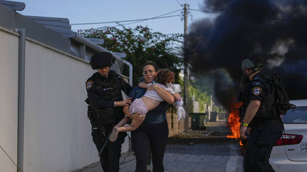 Israelisk polis hjälper en kvinna och ett barn från ett område som träffats av en raket i Ashkelon.