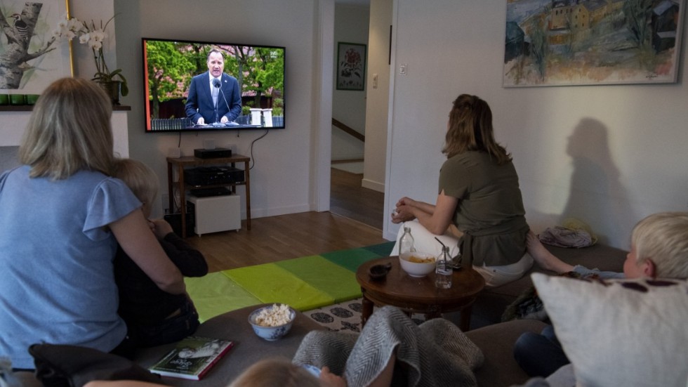 En familj tittar på ett av Stefan Löfvens tv-tal under pandemiåret som gått. Här talar statsministern från Skansen på nationaldagen. 