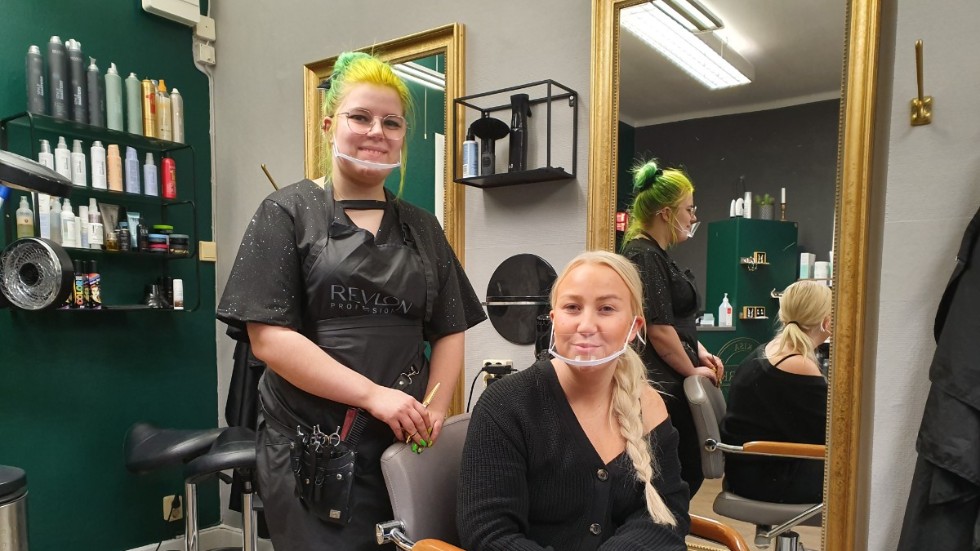 Malin Nilsson bakom frisörstolen och Julia Johansson på Hårverket klipper med visir från och med tisdagen. 