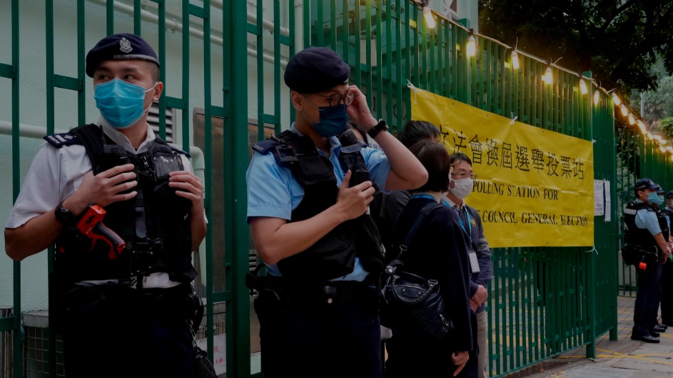 Poliser på vakt utanför en vallokal i Hongkong den 19 december. Det var det första valet som hölls efter att Peking lagstiftade om att alla valbara kandidater skulle vara lojala med kommunistpartiet. Arkivbild.