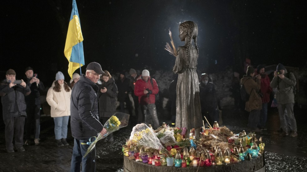 Människor tänder ljus och lägger ner blommor vid monumentet över offren för Holodomor i Kiev. Arkivbild.