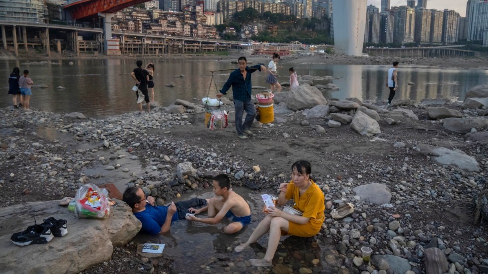 Boende i staden Chongqing försöker svalka sig i pölar som bildats i Jialingfloden, en biflod till Yangtze, när vattennivån sjunkit undan.