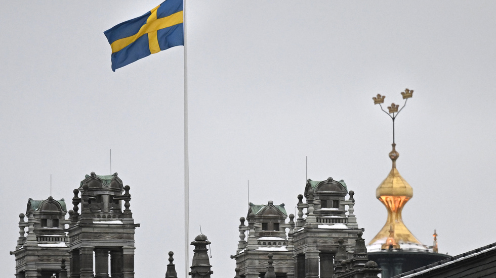 Svenska flaggan över regeringskansliet Rosenbad i Stockholm. I bakgrunden syns stadshusets tre kronor.