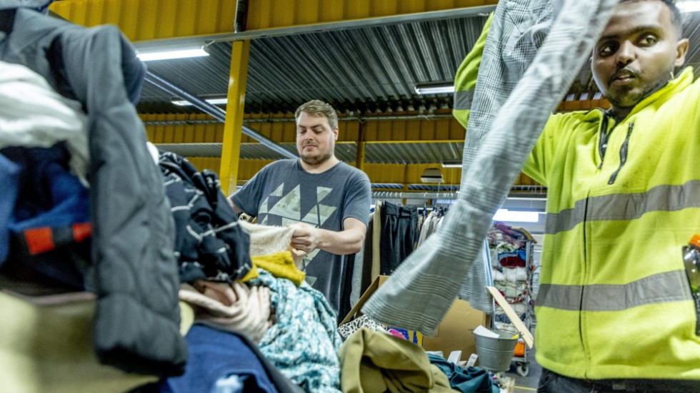 Magnus Schüler och Isak Nur går igenom en av klädhögarna på Myrornas sorteringscentral i Göteborg.