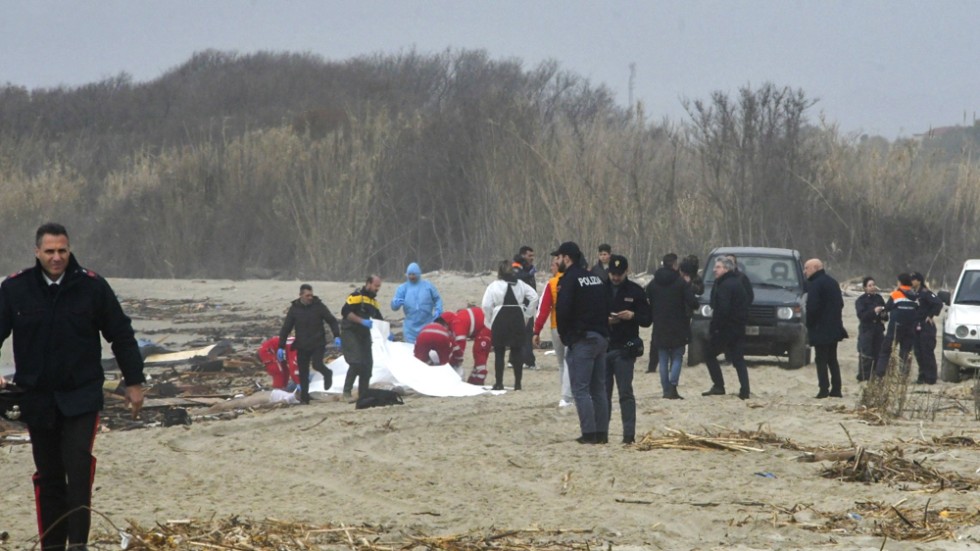Räddningsarbetare i södra Italien tar hand om en av dem som omkommit sedan en båt med migranter kapsejsat i havet utanför.