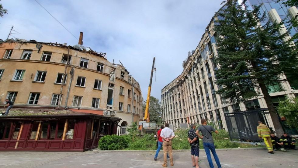 Människor står utanför en byggnad i Lviv som träffats i den ryska raketattacken mot staden.