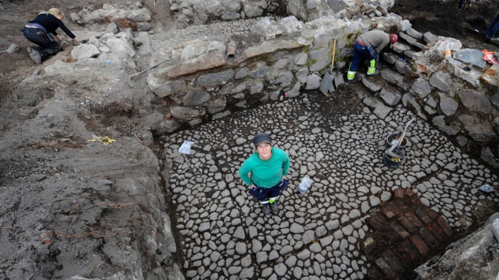 Så här såg det ut för drygt tio år sedan, 2011, när arkeologen Tina Mathiesson från Sörmlands Museum visar upp ett stengolv som hittats under utgrävningarna i Åkroken. 