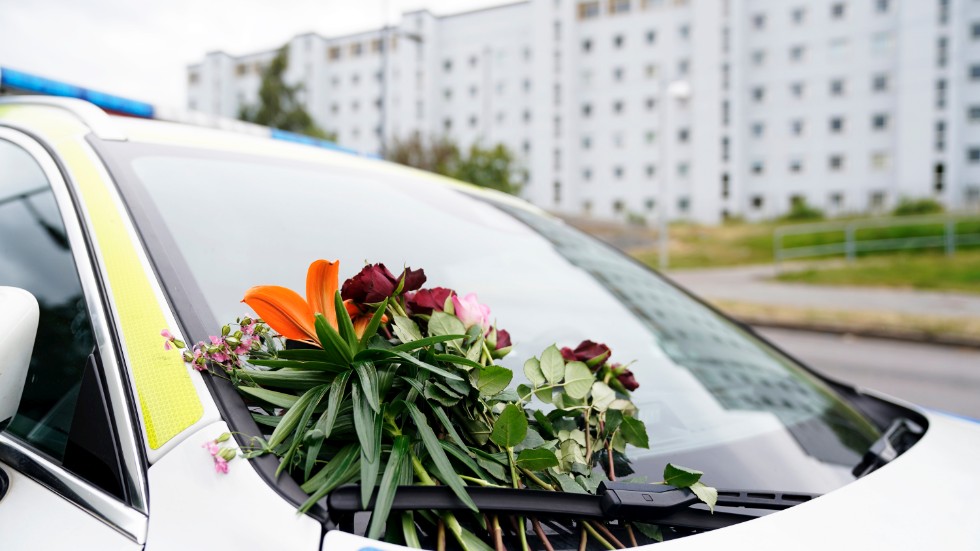 Blommor på en polisbil vid platsen där en polis sköts tills döds i Biskopsgården i Göteborg. 