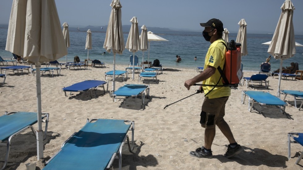 Viruset är fortfarande närvarande. Här desinficeras solstolar på en strand utanför Aten i maj 2021. Arkivbild.