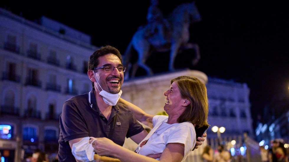 Ett par firar vid torget Puerta del Sol i Madrid efter det att munskyddskravet slopats vid midnatt, natten till den 26 juni.