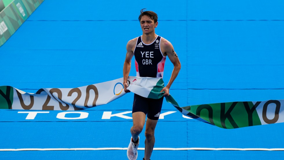Alex Yee springer i mål i triathlons mixedstafett.