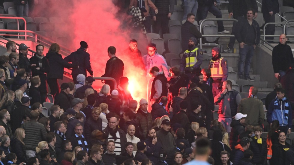 Folk lämnar läktaren efter att supportrar börjat kasta bangers under söndagens fotbollsmatch i allsvenskan mellan Djurgårdens IF och AIK.