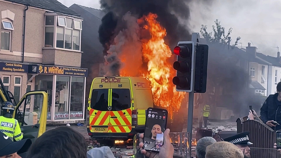 En polisbil antändes när en grupp attackerade räddningsmanskap i Southport.