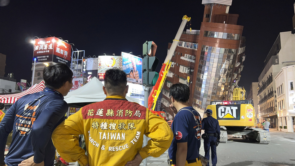 Räddningsarbetare framför en lutande byggnad i Hualien i östra Taiwan.