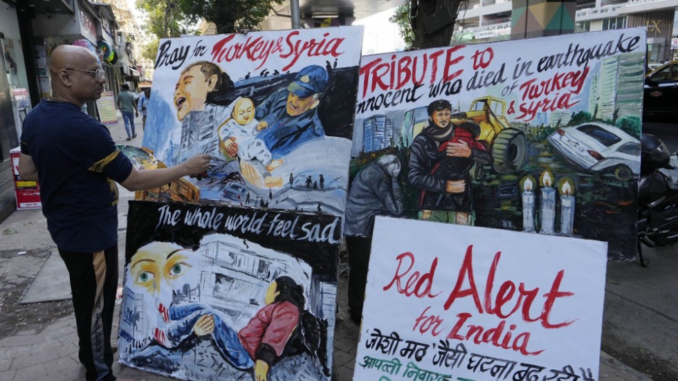 En lärare i Indien målar plakat till stöd för de drabbade i Turkiet och Syrien.