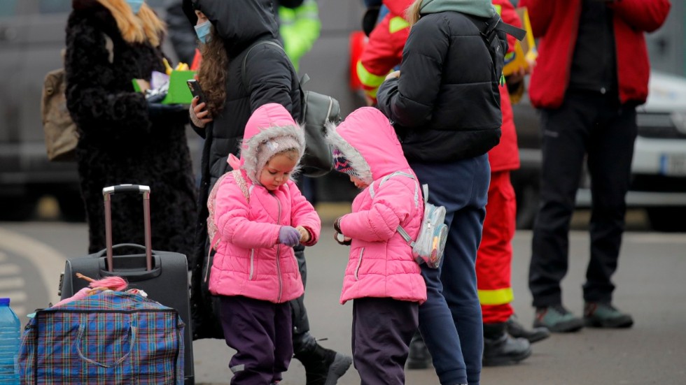 Två ukrainska flickor delar på godis som delats ut av rumänska volontärer vid gränsen mot Ukraina. Sedan krigsutbrottet har hundratusentals människor flytt landet, varav många barn.