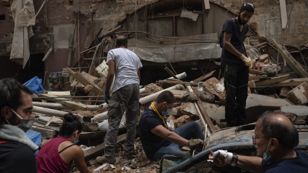 Människor forslar bort bråte från ett förstört hus i Beiruts hamnområde.