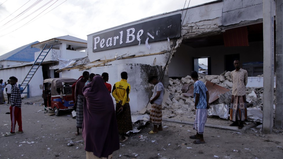 Människor betraktar förstörelsen utanför hotellet Pearl Beach i Somalias huvudstad Mogadishu, som attackerades av terrorgruppen al-Shabab på fredagen.