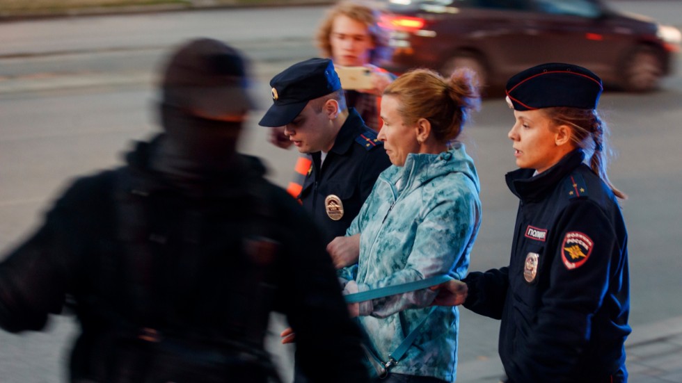 En kvinna leds iväg av poliser vid protester i Jekaterinburg. Den maskerade polisen i förgrunden bär ett "Z", som kommit att bli en rysk symbol till stöd för krigsinsatsen i Ukraina.