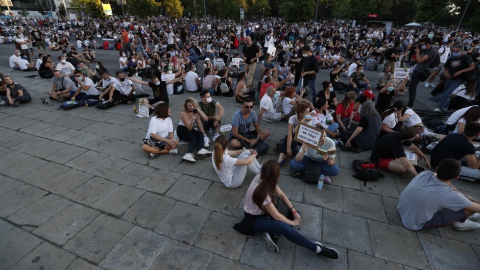 Sittande demonstranter utanför det serbiska parlamentet i torsdags kväll. De serbiska myndigheterna har skrotat sina planer på att införa utegångsförbud i landet men har, efter dagar med våldsamma demonstrationer, infört förbud mot samlingar med fler än tio personer.