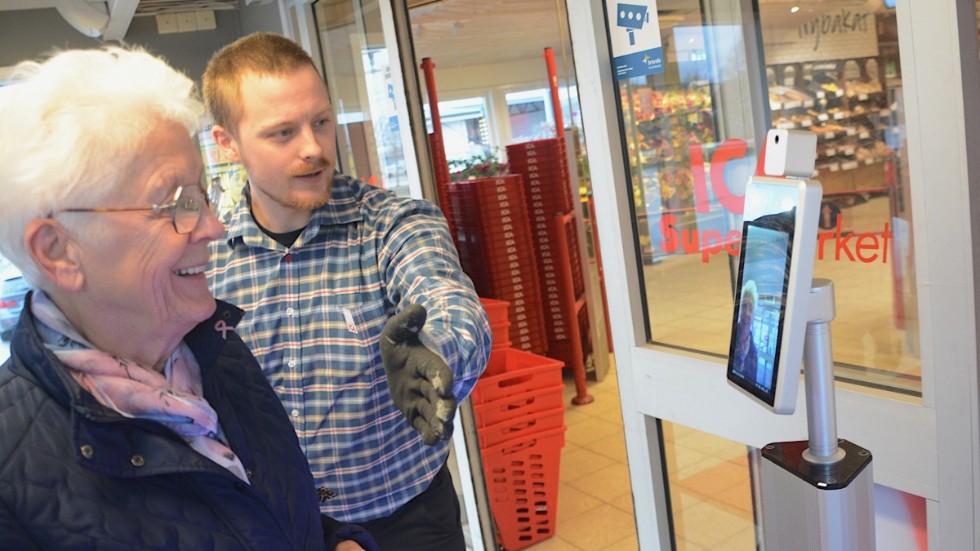 Butikschefen Dennis Dahlin instruerar kunden Gunnel Nilsson hur man kollar tempen innan man går in i butiken. "Det här är en mycket bra idé" tycker hon.
