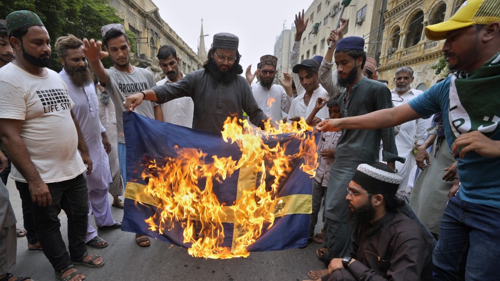 Anhängare till ett radikalt islamistparti i Pakistan bränner ett tygstycke som ska föreställa en svensk flagga i Karachi i fredags förra veckan.