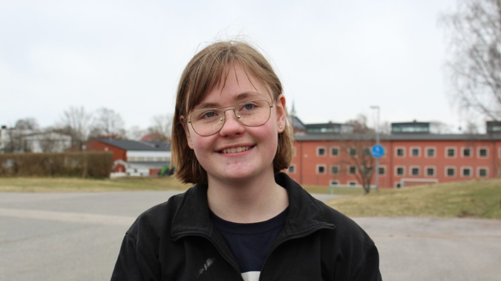 Amanda Karlsson står med Vimmerby Gymnasium i bakgrunden där hon har praoat på Fordons- och Transportsprogrammet. 