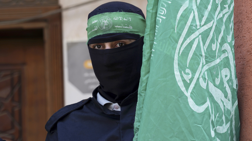 En medlem i den väpnade grenen al-Qassam-brigaderna med Hamas flagga, vid en demonstration mot Israel i Gazaremsan i våras.