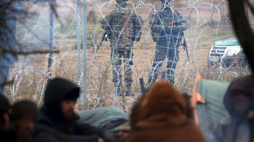 Polska gränsvakter ses från den belarusiska sidan av gränsen vid orten Grodno, där ett okänt antal migranter uppehåller sig i hopp om att komma in i Polen och vidare i Europa.