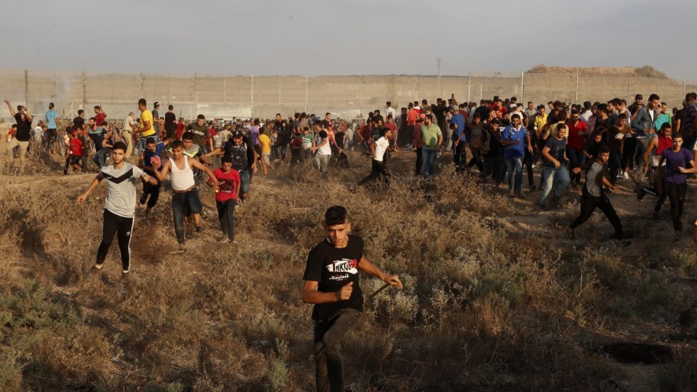 Palestinska demonstranter flyr undan tårgas avfyrad av israelisk militär under våldsamma protester vid gränsen mellan Gaza och Israel lördagen den 21 augusti.