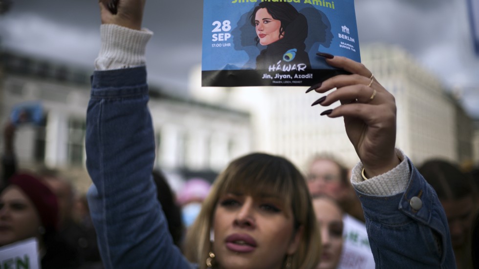 En kvinna håller upp ett flygblad med den dödade Mahsa Jîna Amini under en protest i Berlin.