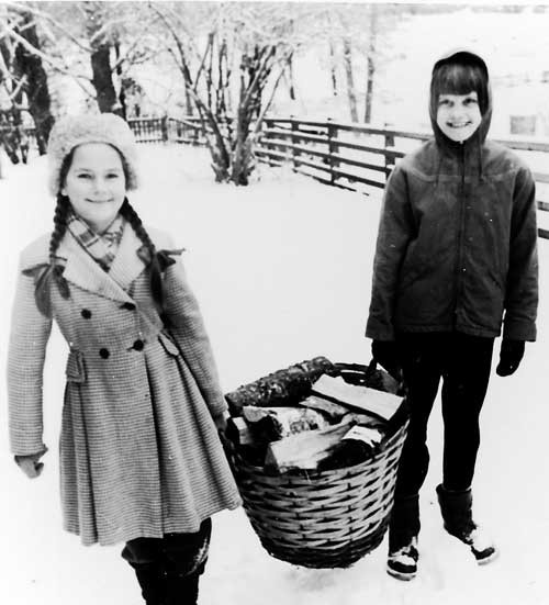 Karin Lönnkvist och Kristina Rydh hjälps åt med vedkorgen. Bilden är tagen 1959 eller möjligen 1960. Foto: Vimmerby Digitala Bildarkiv