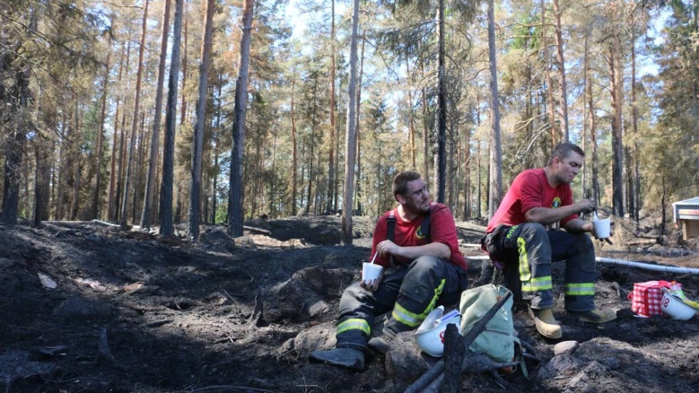 Samuel Svensson, th, får en efterlängtad och välbehövlig paus i arbetet med den stora skogsbranden i Mellingerum.  Hans första som deltidsbrandman. På bilden också kollegan Jonathan Petersson.