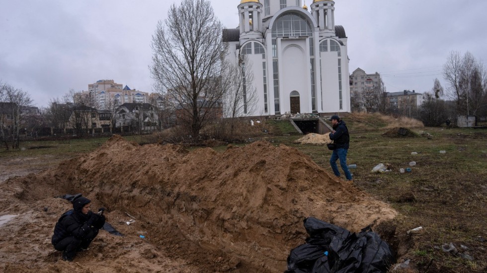 Journalister dokumenterar en massgrav vid kyrkan i den ukrainska staden Butja söndagen den 3 april.