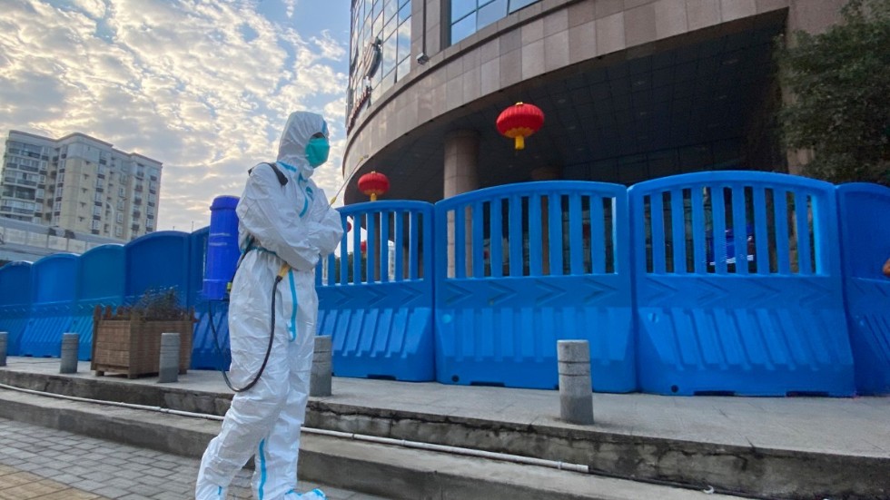 En person i skyddskläder utanför ett sjukhus i Wuhan i Kina. Nu gör WHO ett nytt försök att hitta coronavirusets ursprung. Arkivbild.