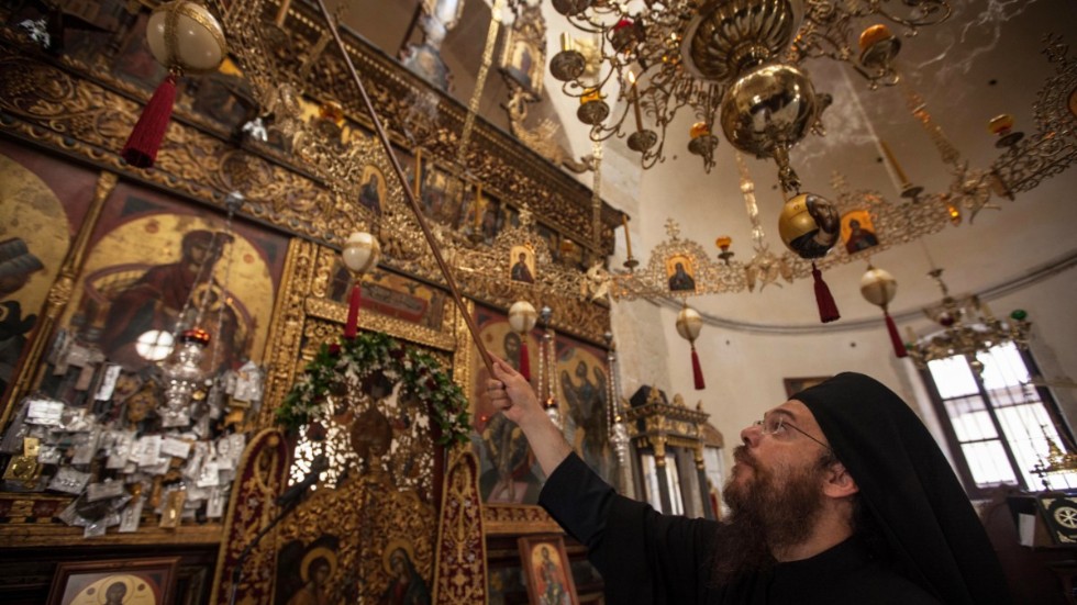 En munk släcker stearinljus i ett kloster på Kreta under det ortodoxa kyrkomötet där i juni 2016.