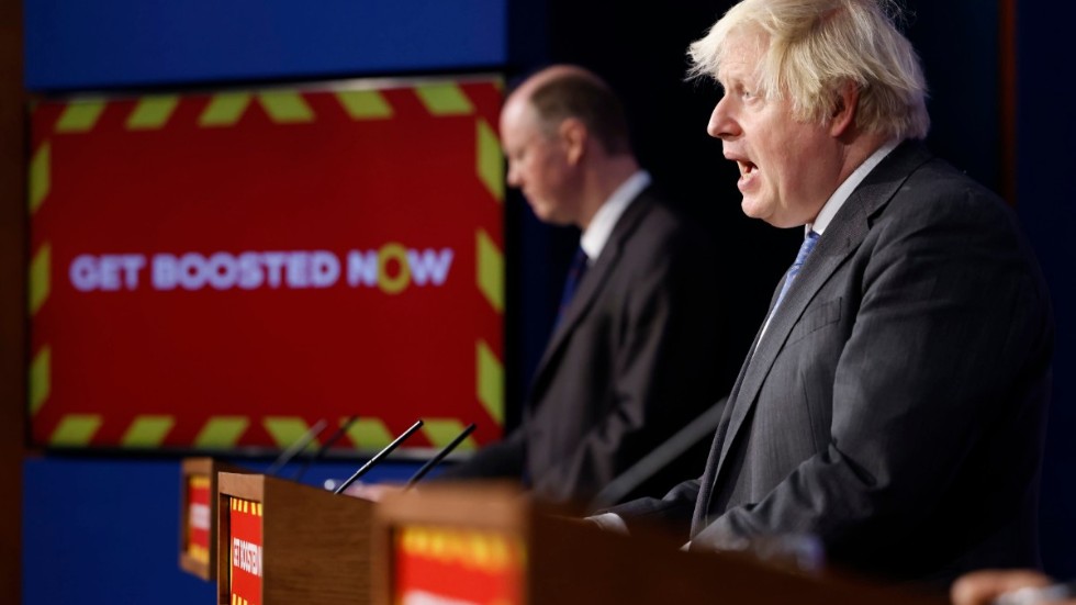 Boris Johnson (närmast kameran) och Chris Whitty på en presskonferens i förra veckan. Skylten uppmanar britterna att ta en tredje vaccinspruta.