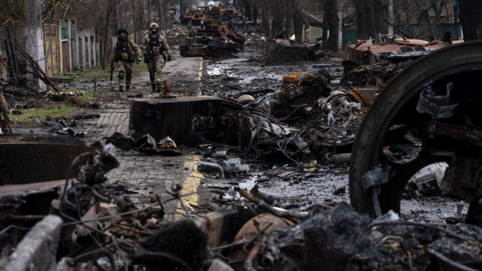 Soldater vandrar vid förstörda ryska stridsvagnar i staden Butja i utkanten av huvudstaden Ukraina. Arkivbild.