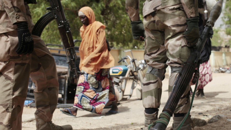 En kvinna går förbi två nigerianska soldater i Gwoza i nordöstra Nigeria 2015, strax efter det att staden befriats från Boko Haram.