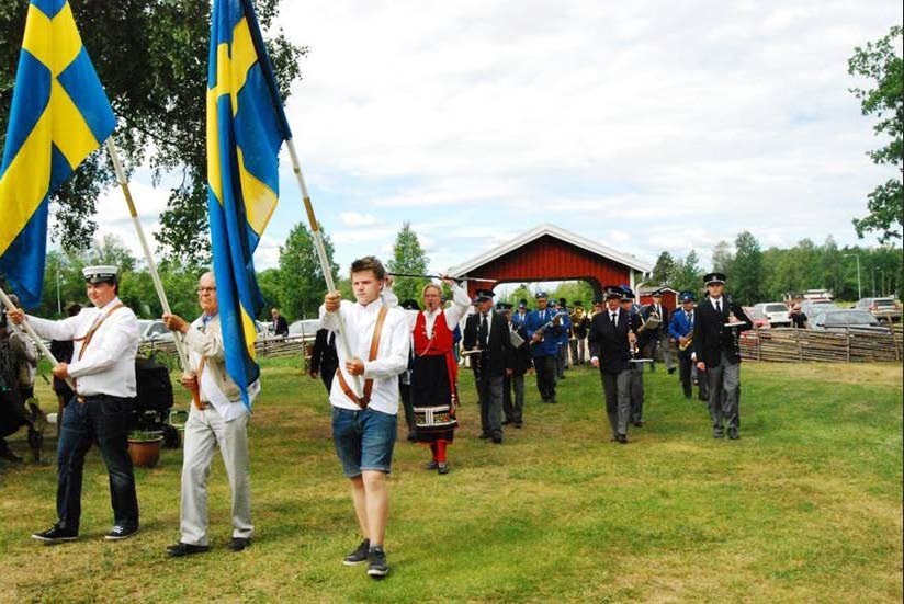 Rosenfors och Vena Musikkårer marscherar tillsammans med fanbärare från Venhagskolan till hembygdsparken.