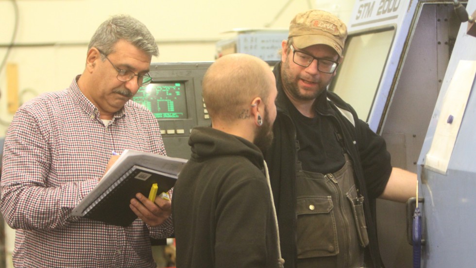 Johnny Nilsson (th) ger Markus instruktioner i det dagliga arbetet på Stora Mossen. Produktionsledaren Arkan Abdulkarim antecknar i sina papper.