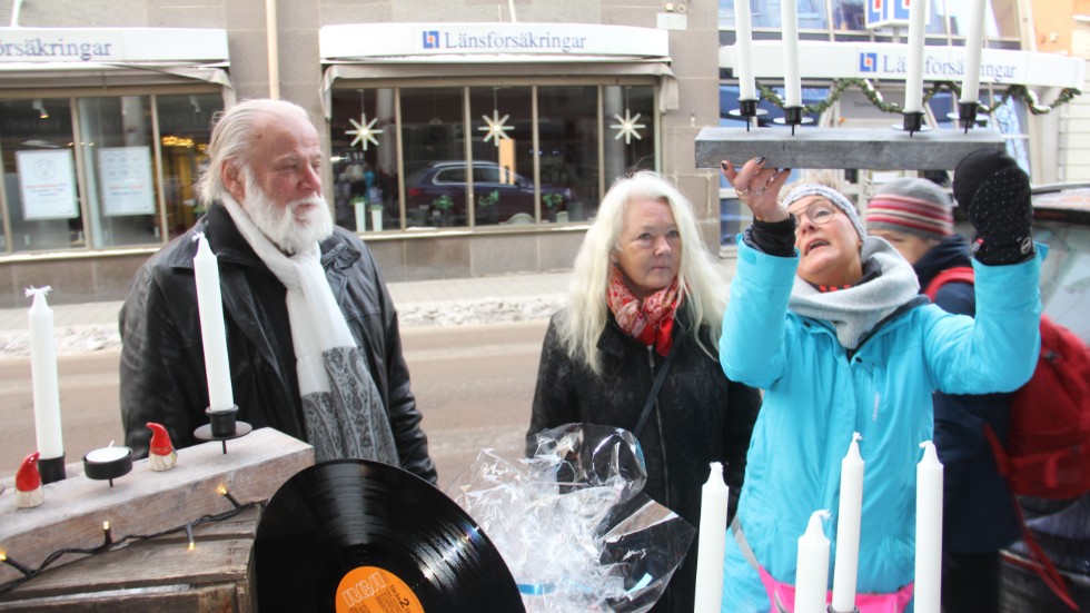 Leif Ericsson och Elsa Hjelm granskar en av de egenhändigt tillverkade ljusstakar som Ylva Eklund saluförde på Drottninggatan. 