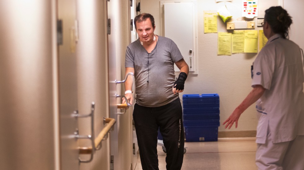 Mattias tar några stapplande steg under uppsikt av sjukhuspersonal. 